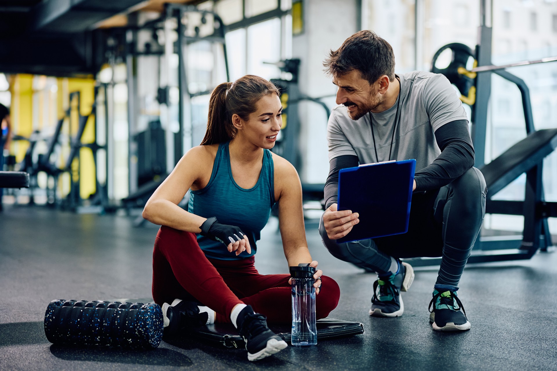 Personal instructor and athletic woman going through exercise plans in a gym.